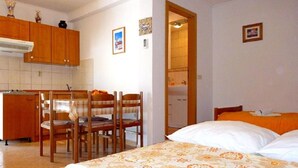 Une chambre à coucher avec un lit, un bureau et une chaise. On peut apercevoir une salle de bain à travers une porte ouverte.