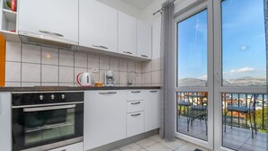 Una cucina moderna con mobili bianchi, forno integrato e macchina per il caffè.