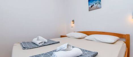 Hotelkamer met een bed, twee kussens, een aan de muur hangend schilderij en een klein wandlampje.