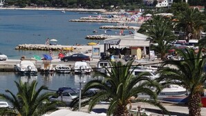 Una marina con imbarcazioni ormeggiate, un piccolo edificio con la scritta 'PORT' e palme sullo sfondo.