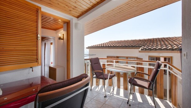 A balcony with a wooden ceiling, a glass table, and two chairs. - Apartment Ante M (Brela)