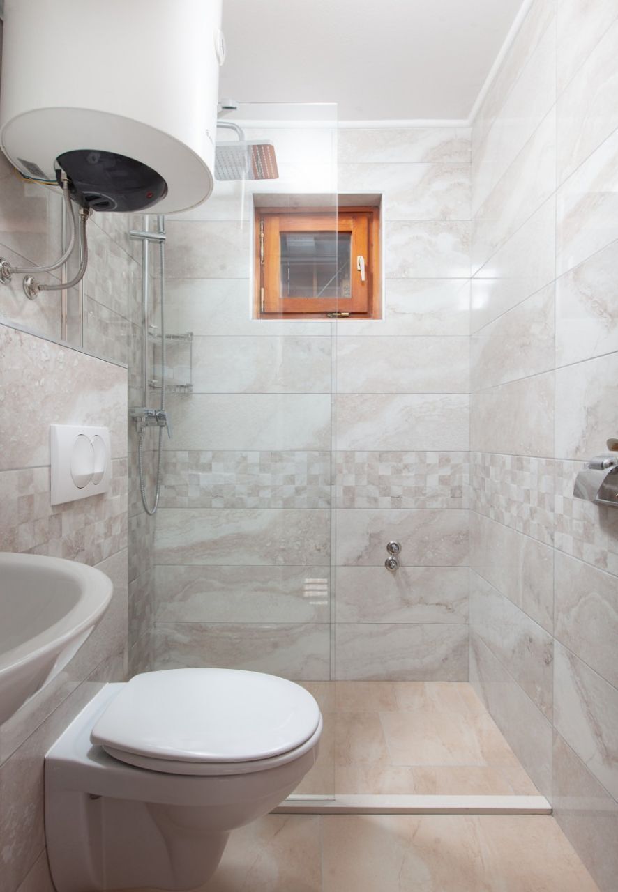 Egy modern fürőszoba üveg válaszfallal ellátott zuhanyzóval, WC-vel és mosdókagylóval.