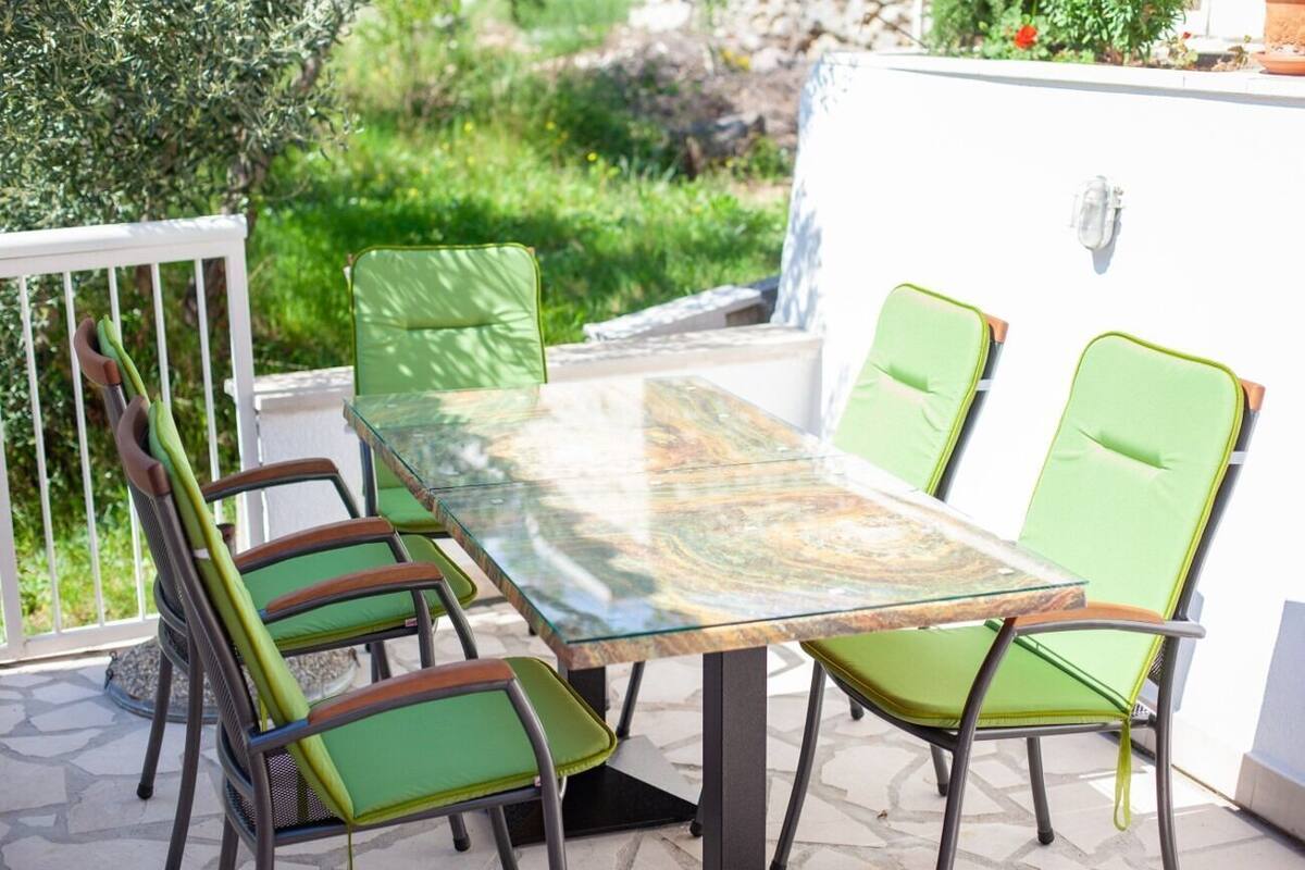 A patio with a glass-top table and four green chairs.
