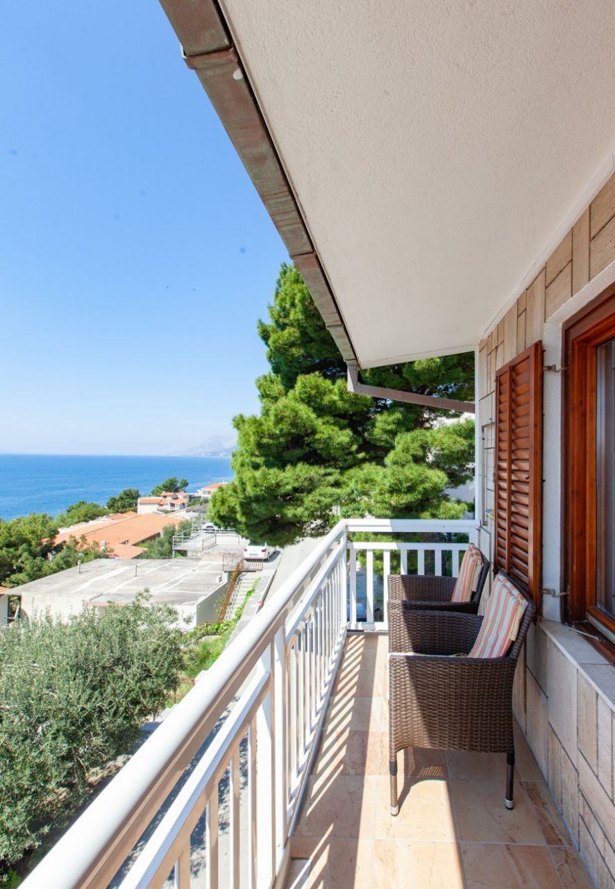 A balcony with a wicker chair and a view of the sea.