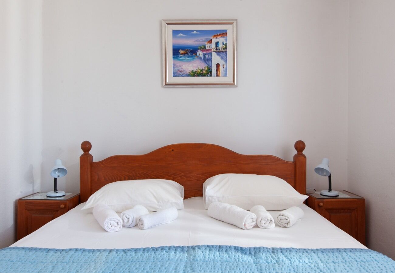 Un lit bien fait, avec du linge de lit et des serviettes blanches, une tête de lit en bois et deux tables de chevet avec des lampes.