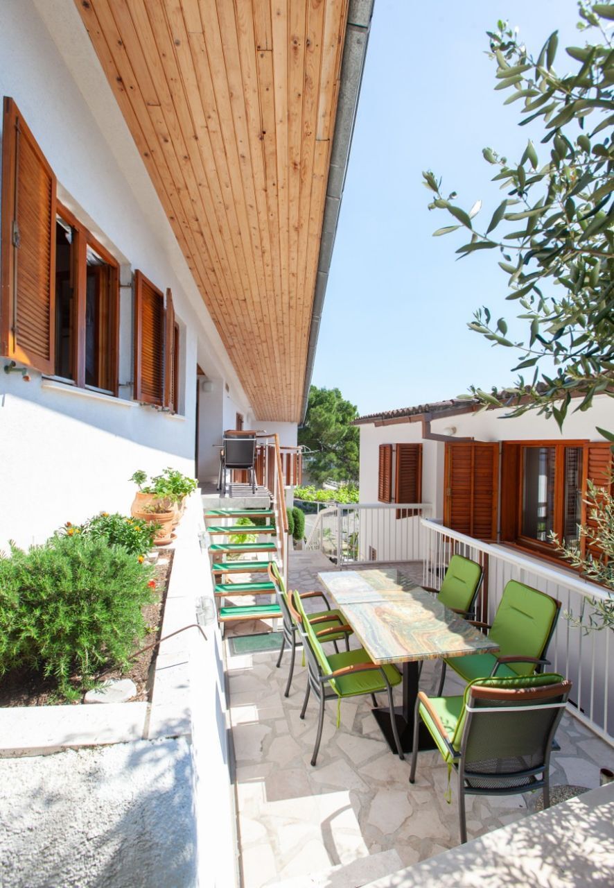 Une terrasse extérieure dotée d’un plafond en bois, de chaises vertes et d’une table.
