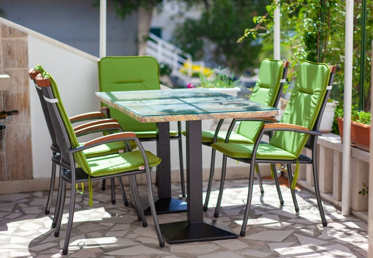 Eine Terrasse mit einem Glastisch und vier grünen Stühlen.