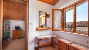 A bedroom with a wooden ceiling, a wooden dresser, a bedside table, and a window with a view of the roof. - Apartment Ante M (Brela)