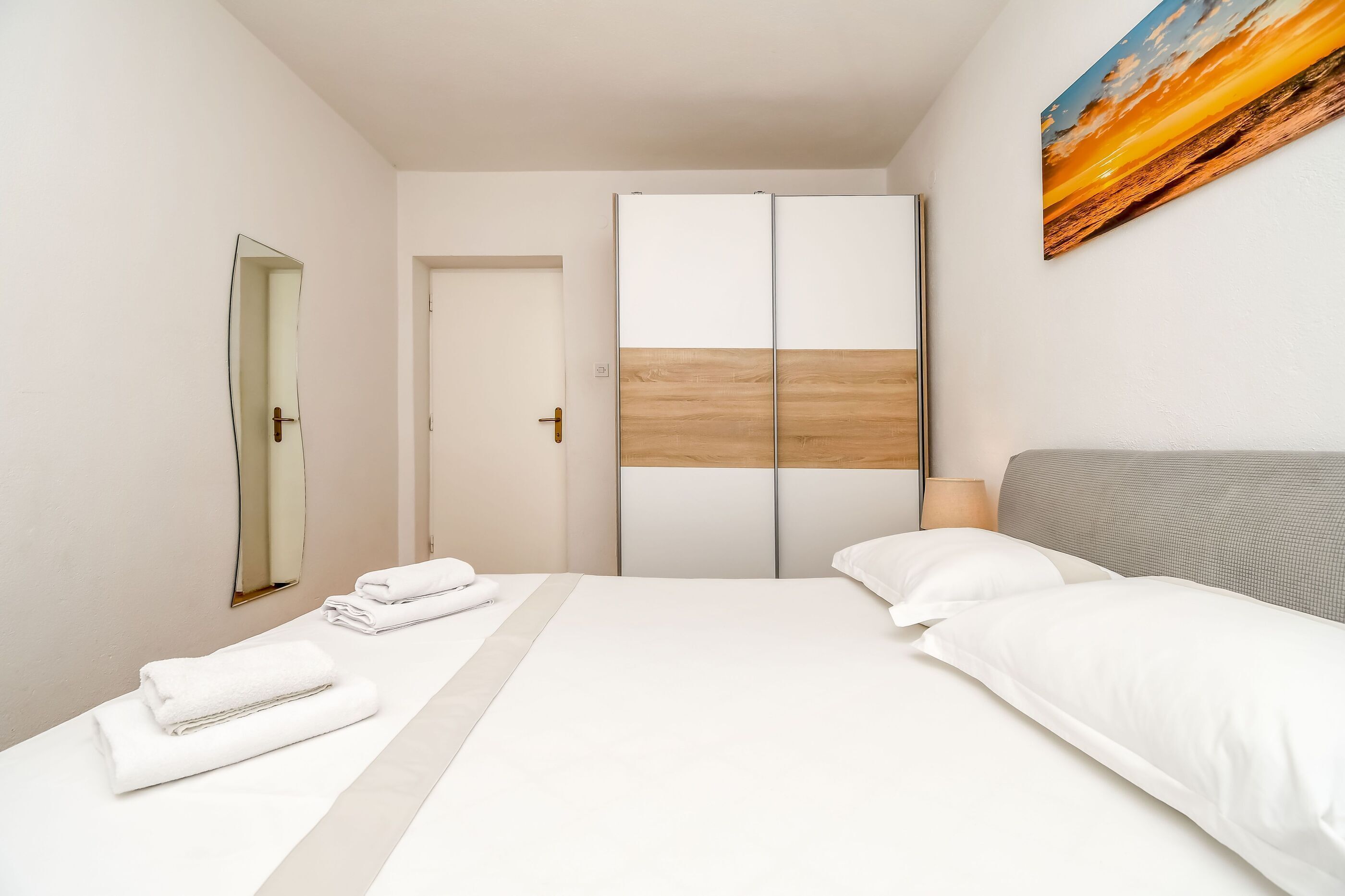Et moderne hotelværelse med en stor seng, et garderobeskab, et spejl og et billede på væggen.