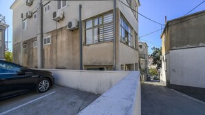A narrow urban street with a black car parked on the left. - Apartment Zeljko (Makarska)