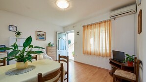 A dining area with a table, chairs, a television, and potted plants. - Apartment Ivanka (Trogir)