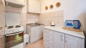 A kitchen with a stove, sink, cabinets, and decorative plates on the wall. - Apartment Ivanka (Trogir)