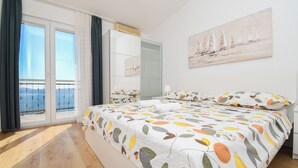 A bedroom with a large bed, a balcony with a view, a painting on the wall, and a mirror. - Apartments Rose (Seget)