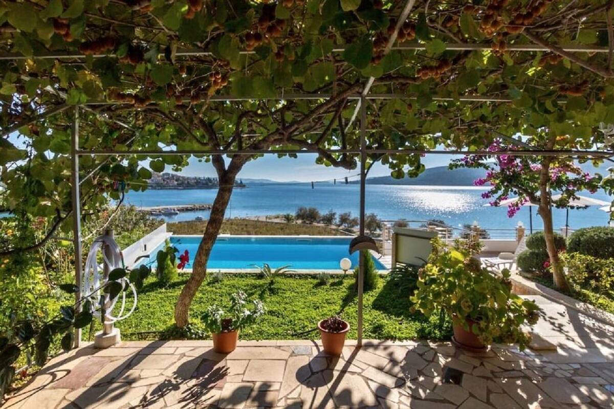 A poolside area with a view of the sea, potted plants, and a pergola structure.