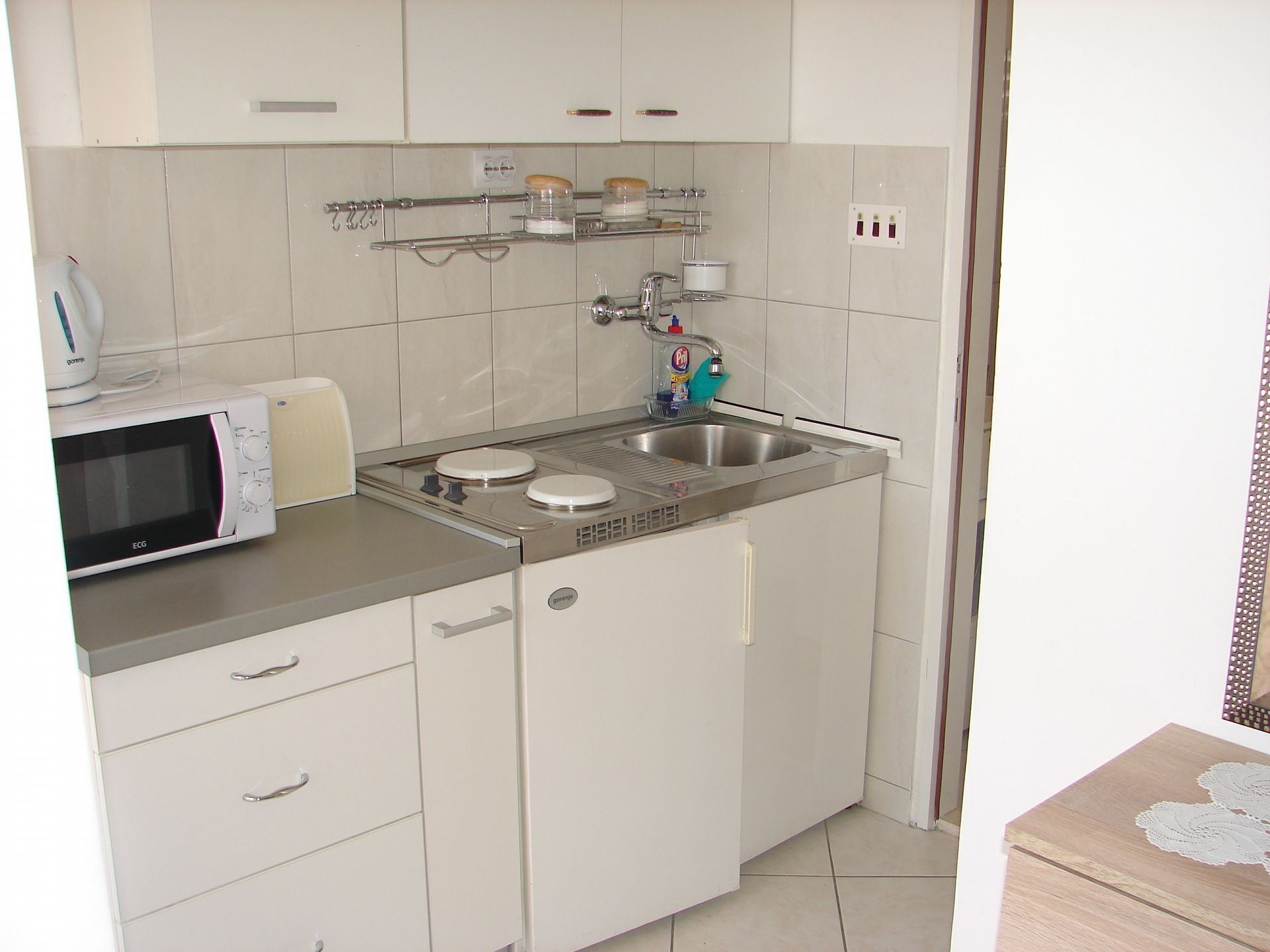 Une cuisine compacte équipée d’un four à micro-ondes, d’une cuisinière, d’un évier et de placards de rangement.