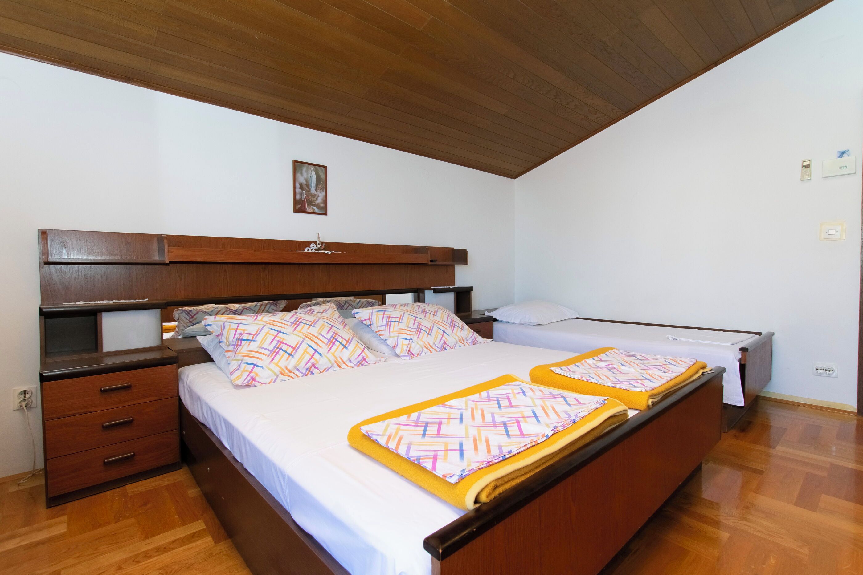 Un dormitorio con dos camas, cabeceros de madera, una mesita de noche y un aparador.