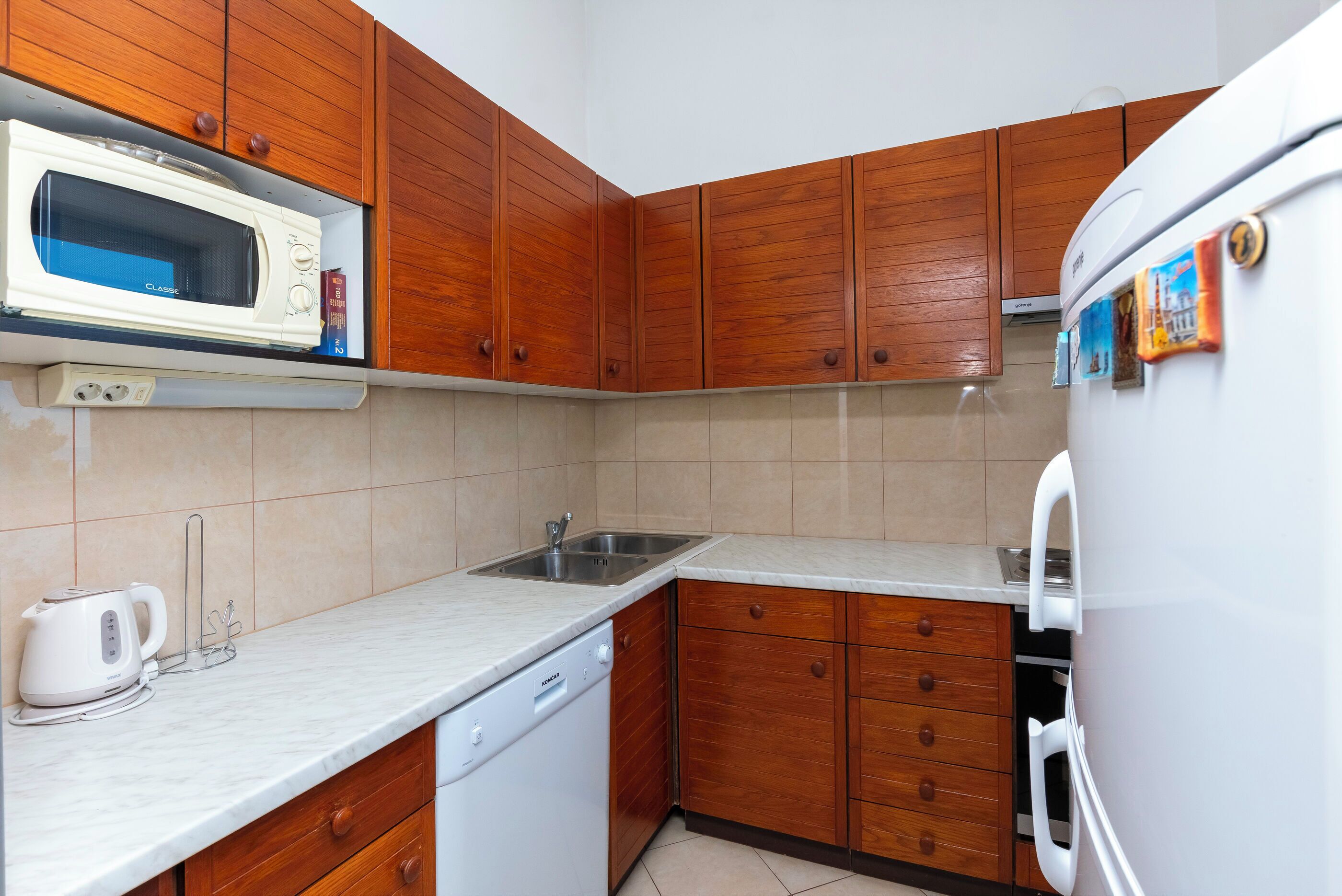 A kitchen with wooden cabinets, a microwave, a dishwasher, and a refrigerator.