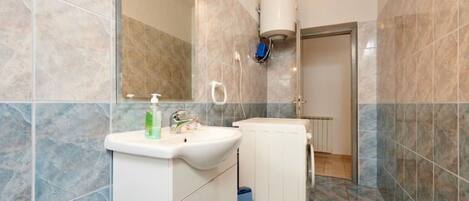 A bathroom with a white sink, a mirror, and a shower area.