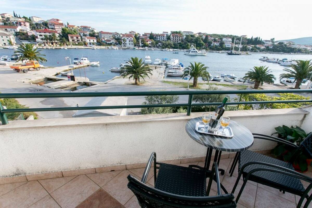A balcony with a table and chairs overlooking a marina with boats and buildings in the background.