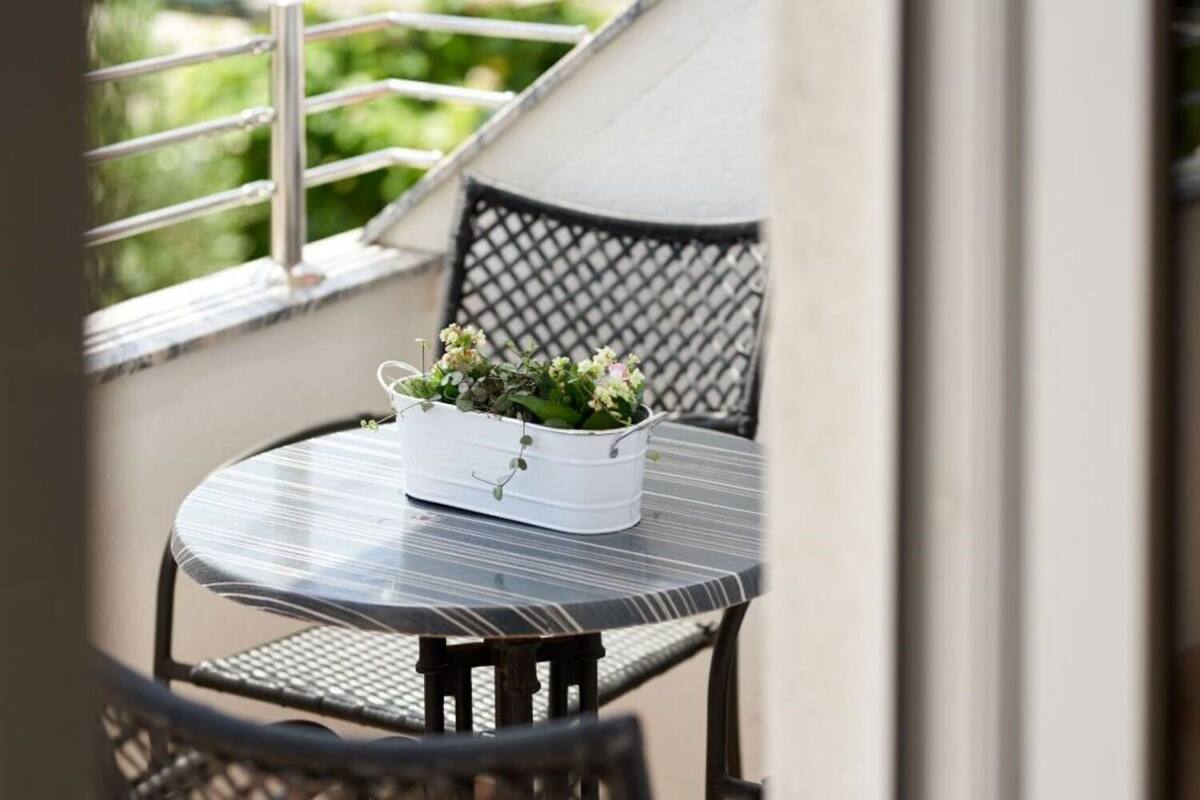 A small round table with a white planter containing green plants and flowers.