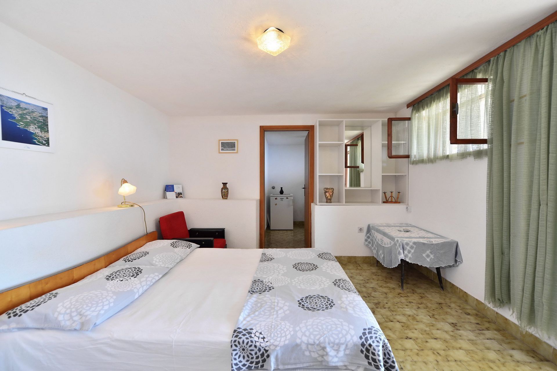Een slaapkamer met een bed, een bureau, een stoel, een spiegel en een klein tafeltje.