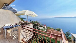 Ein Balkon mit Tisch und Stühlen mit Blick auf ein Gewässer.