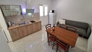 Una cocina compacta con comedor, refrigerador y sofá.