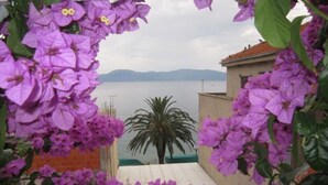 Un balcón con flores moradas y vistas al mar.