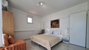 Un dormitorio moderno con una cama grande, un armario de madera, un ventanal pequeño y un cuadro en la pared.