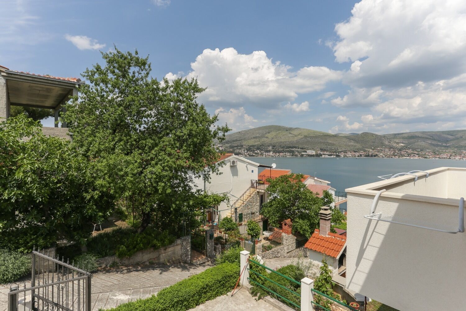 Une ville côtière avec des maisons à étages, une vue dégagée sur la mer et un paysage vallonné en arrière-plan.