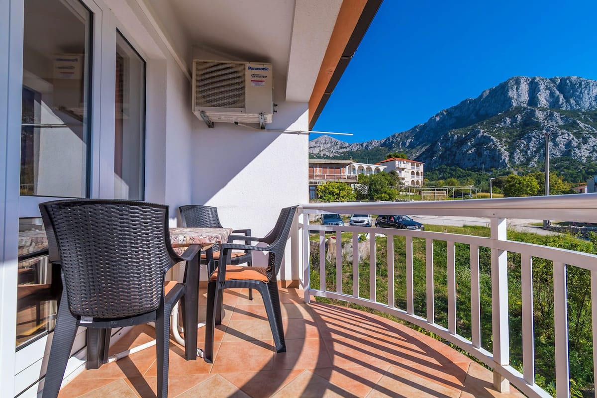 A balcony with a table and chairs, overlooking a mountain and a building.