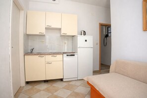 A compact kitchen with a refrigerator, a sink, and cabinets. - Apartments Tiho (Podgora)