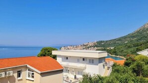 A coastal town with buildings, a clear blue sky, and a view of the sea. - Apartments Tiho (Podgora)