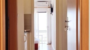 A hallway with a tiled floor leading to a room with a bed and a window. - Apartments Tiho (Podgora)