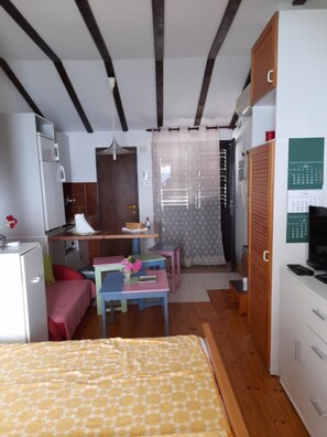 A compact room with a bed, a small kitchenette, a dining area with a table and chairs, and a wardrobe. - Apartment Danka (Gradac)