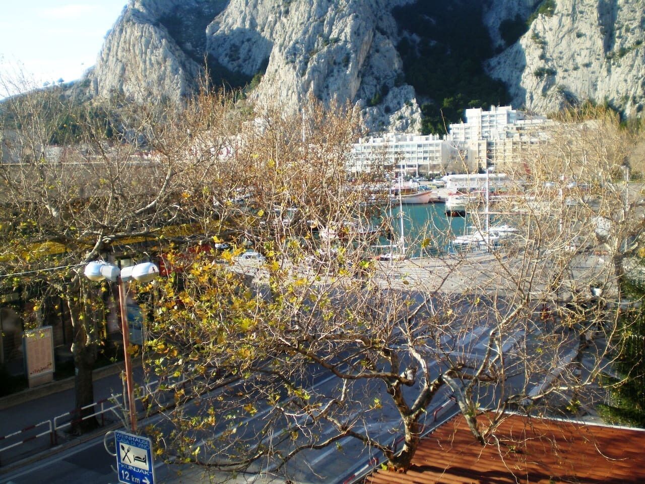 Eine Küstenlandschaft mit Bergeltern, einer Marina mit Booten und einem Gebäude mit Balkonen.