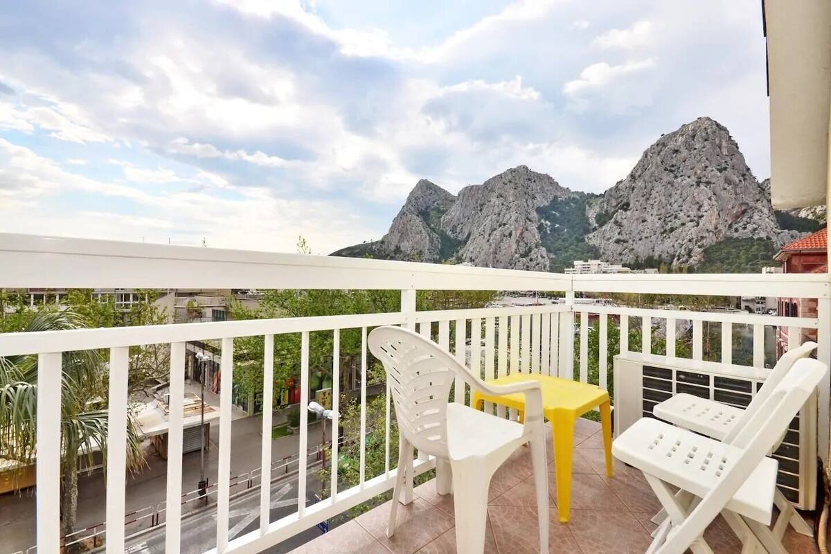 A balcony with white railings, a yellow table, and white chairs.