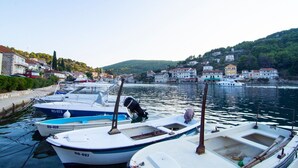 A marina with several boats docked, a clear view of the surrounding buildings, and a hilly landscape in the background. - Apartments Mari (Solta)