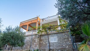 A stone-walled building with a balcony and a separate orange-roofed structure. - Apartments Mari (Solta)