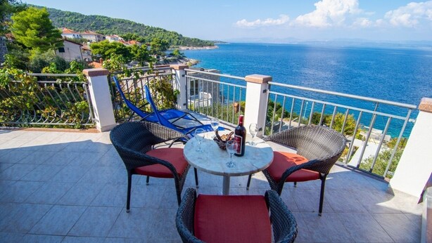 A terrace with wicker chairs and a table, overlooking a coastal view. - Apartments Mari (Solta)
