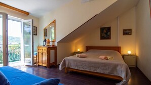 A bedroom with a bed, bedside tables, a dresser, a mirror, and a balcony with a view. - Apartments Mari (Solta)