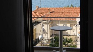 A balcony with a table and chairs, overlooking a body of water and distant mountains. - Apartments Nik (Gradac)