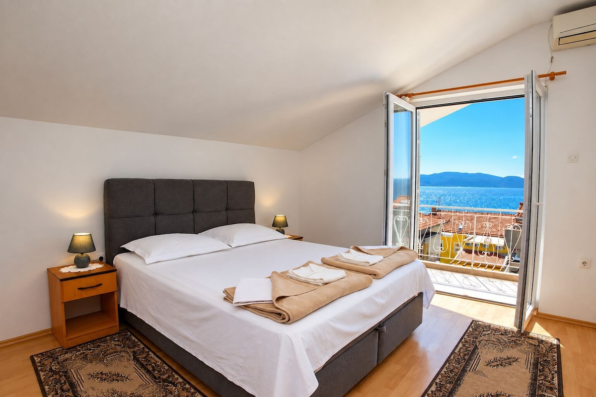Una camera da letto con un letto, lampade sui comodini, vista mare e un balcone.