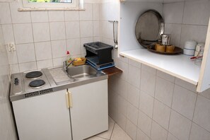 A compact kitchen with a sink, stove, and a small window. - Apartments Nik (Gradac)