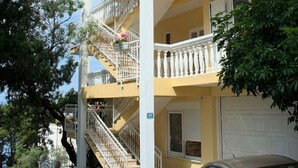 A multi-story building with balconies, a staircase, and a parked car. - Apartment Gojko (Podgora)
