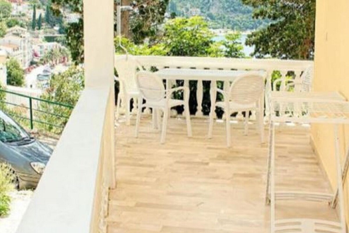 A balcony with a wooden floor and white chairs.