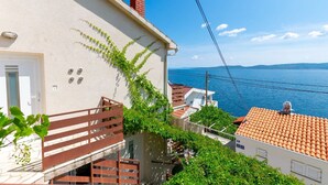A coastal building with a white exterior, red-tiled roof, and a view of the sea. - Apartment Mirja (Omis)