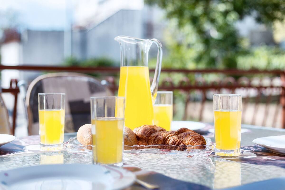 A breakfast table with croissants, juice glasses, and a pitcher of orange juice.