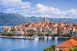 A coastal town with historic buildings, a prominent tower, and a marina with boats. - Apartment Jakica (Korčula)