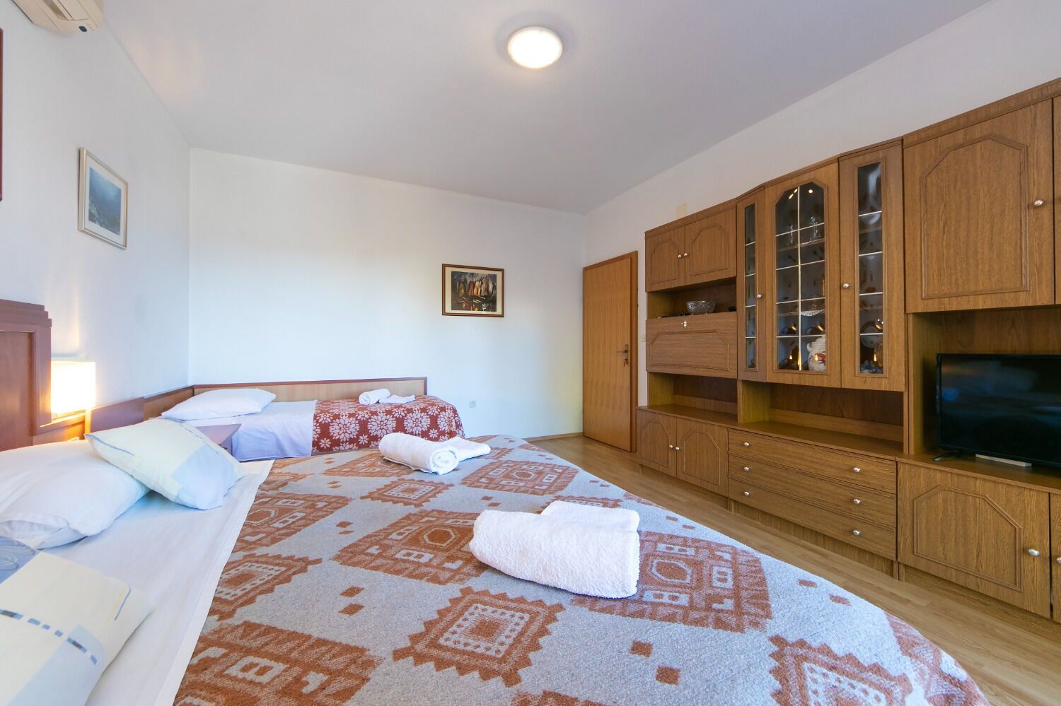 Habitación de hotel con una cama grande, televisor, armarios de madera y un cuadro en la pared.